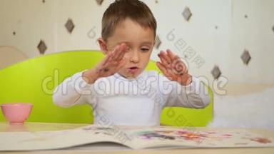 一个淘气的男孩拿颜料在纸上拍掌。孩子的发展、<strong>教育</strong>、<strong>心理</strong>、情感。